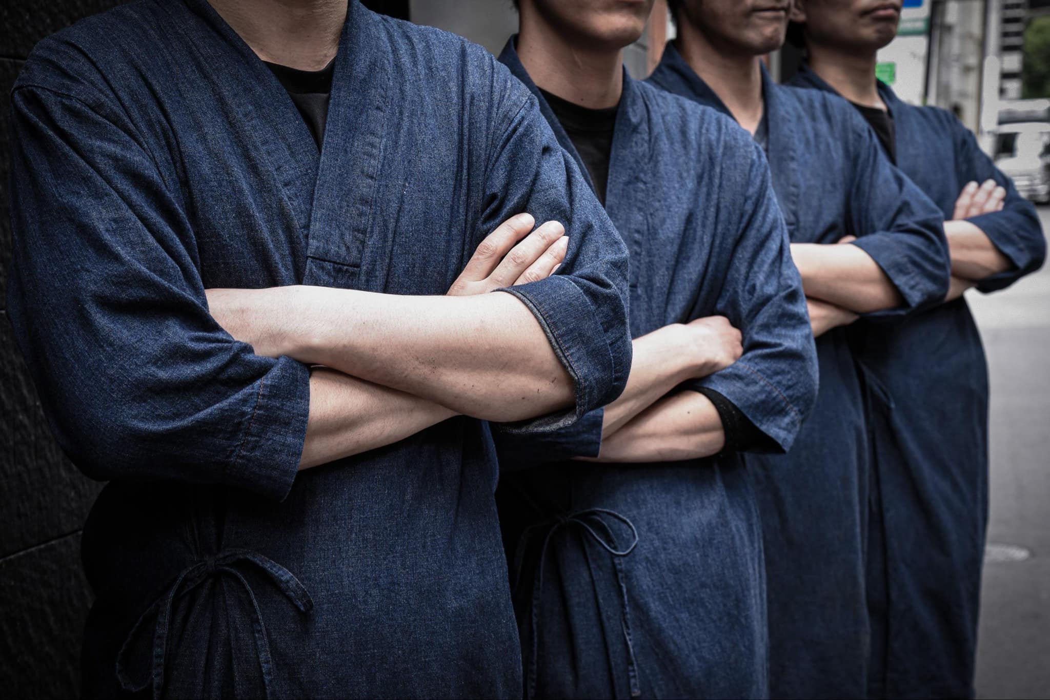 紺色の制服を着て腕を組み、並んで立つ複数のスタッフ