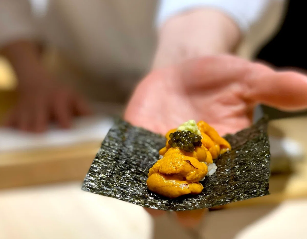 手の上の海苔にウニとキャビアをのせた一品