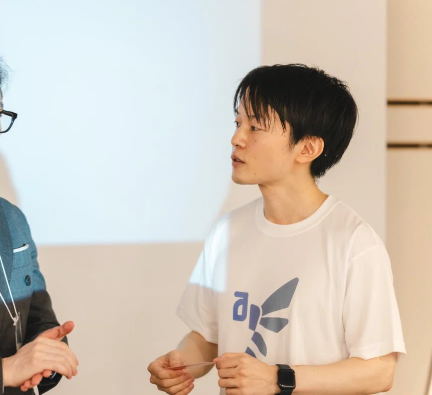 AIDBのロゴ入りTシャツを着て話す水谷健さん