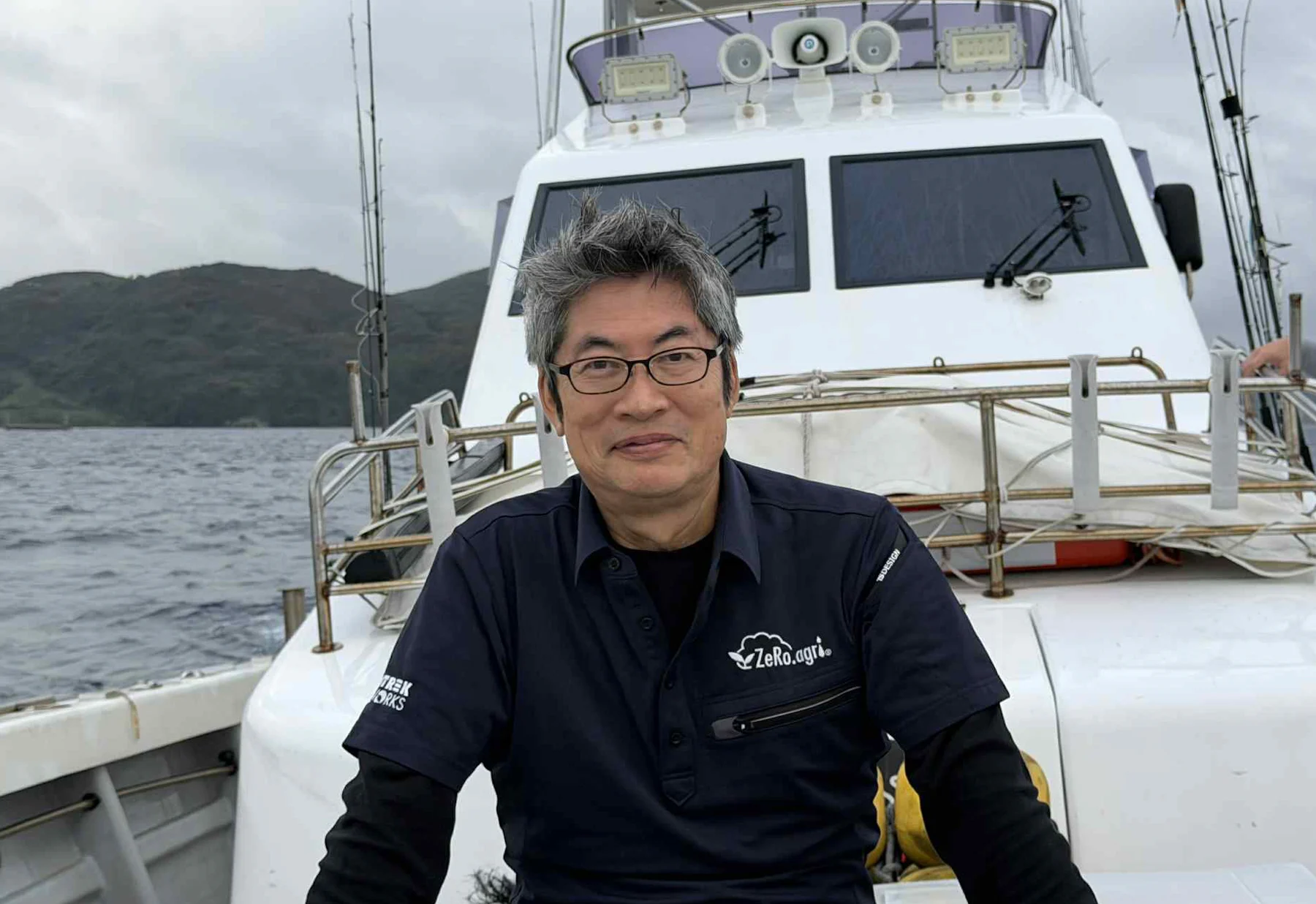 釣り船の上で座る佐々木伸一さん