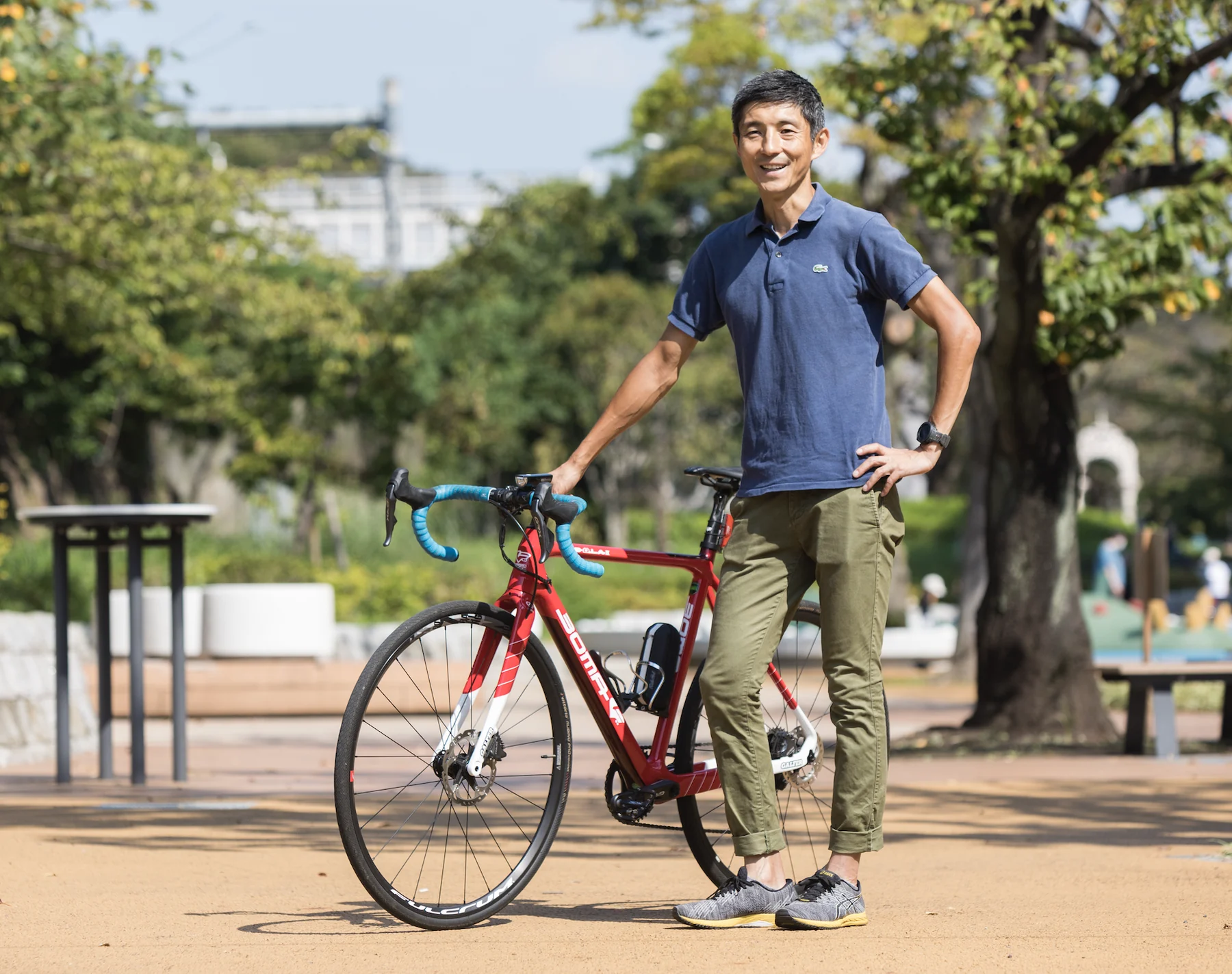 赤いロードバイクの隣に立つ福田隆さん
